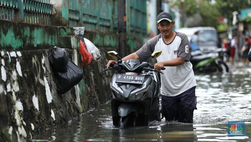 Warga beraktifitas saat banjir setinggi 60 cm menggenangi kawasan Pesing Koneng, Jakarta, Senin (27/2/2023). (CNBC Indonesia/Tri Susilo)