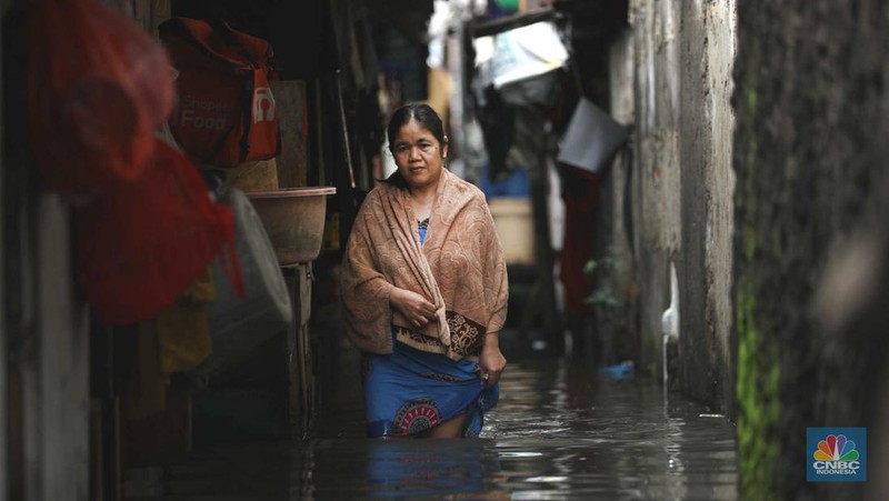 Warga beraktifitas saat banjir setinggi 60 cm menggenangi kawasan Pesing Koneng, Jakarta, Senin (27/2/2023). (CNBC Indonesia/Tri Susilo)