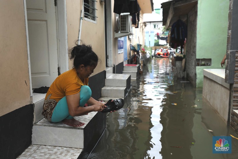 Warga beraktifitas saat banjir setinggi 60 cm menggenangi kawasan Pesing Koneng, Jakarta, Senin (27/2/2023). (CNBC Indonesia/Tri Susilo)