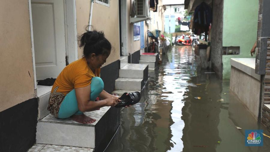 Warga beraktifitas saat banjir setinggi 60 cm menggenangi kawasan Pesing Koneng, Jakarta, Senin (27/2/2023). (CNBC Indonesia/Tri Susilo)