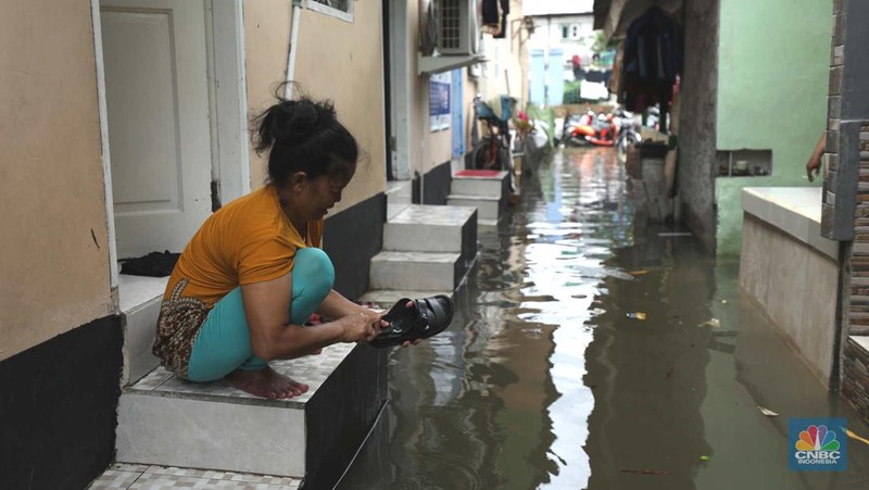 Warga beraktifitas saat banjir setinggi 60 cm menggenangi kawasan Pesing Koneng, Jakarta, Senin (27/2/2023). (CNBC Indonesia/Tri Susilo)