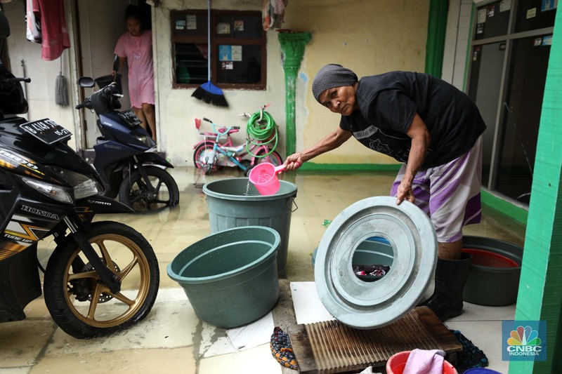 Warga beraktifitas saat banjir setinggi 60 cm menggenangi kawasan Pesing Koneng, Jakarta, Senin (27/2/2023). (CNBC Indonesia/Tri Susilo)