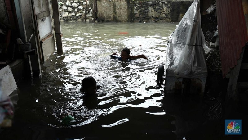 Warga beraktifitas saat banjir setinggi 60 cm menggenangi kawasan Pesing Koneng, Jakarta, Senin (27/2/2023). (CNBC Indonesia/Tri Susilo)