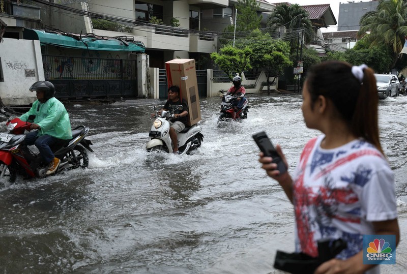 Warga menyelamatkan hewan peliharaannya untuk melewati genangan banjir di Kawasan Green Garden, Jakarta, Senin (27/2/2023). (CNBC Indonesia/Tri Susilo)