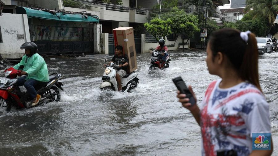 Warga menyelamatkan hewan peliharaannya untuk melewati genangan banjir di Kawasan Green Garden, Jakarta, Senin (27/2/2023). (CNBC Indonesia/Tri Susilo)
