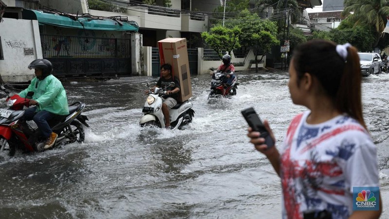 Warga menyelamatkan hewan peliharaannya untuk melewati genangan banjir di Kawasan Green Garden, Jakarta, Senin (27/2/2023). (CNBC Indonesia/Tri Susilo)