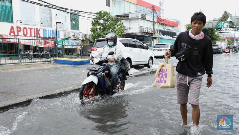 Warga menyelamatkan hewan peliharaannya untuk melewati genangan banjir di Kawasan Green Garden, Jakarta, Senin (27/2/2023). (CNBC Indonesia/Tri Susilo)