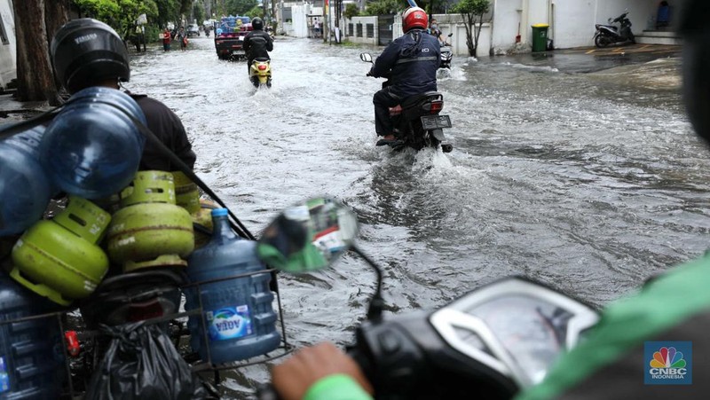 Warga menyelamatkan hewan peliharaannya untuk melewati genangan banjir di Kawasan Green Garden, Jakarta, Senin (27/2/2023). (CNBC Indonesia/Tri Susilo)