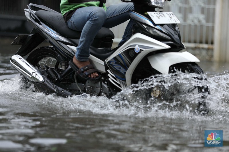Warga menyelamatkan hewan peliharaannya untuk melewati genangan banjir di Kawasan Green Garden, Jakarta, Senin (27/2/2023). (CNBC Indonesia/Tri Susilo)