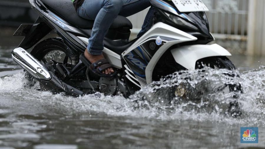 Warga menyelamatkan hewan peliharaannya untuk melewati genangan banjir di Kawasan Green Garden, Jakarta, Senin (27/2/2023). (CNBC Indonesia/Tri Susilo)