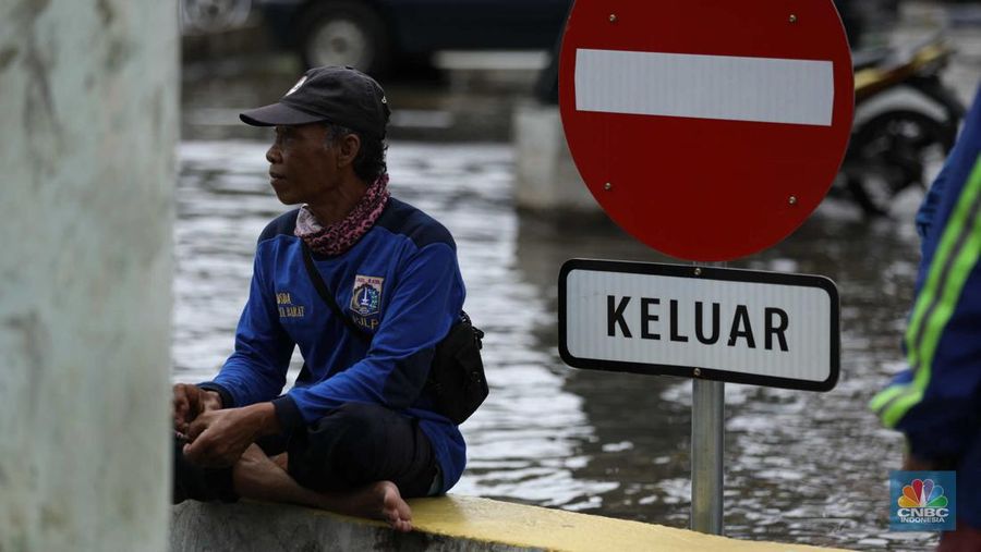 Warga menyelamatkan hewan peliharaannya untuk melewati genangan banjir di Kawasan Green Garden, Jakarta, Senin (27/2/2023). (CNBC Indonesia/Tri Susilo)