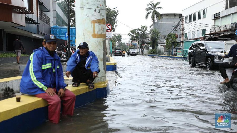 Warga menyelamatkan hewan peliharaannya untuk melewati genangan banjir di Kawasan Green Garden, Jakarta, Senin (27/2/2023). (CNBC Indonesia/Tri Susilo)