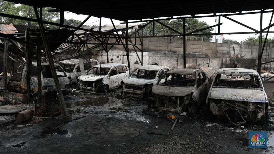 Warga melewati kendaraan yang hangus terbakar di lokasi terdampak kebakaran Depo Pertamina Plumpang di Kampung Tanah Merah Bawah, Koja, Jakarta Utara, Sabtu (4/3/2023). (CNBC Indonesia/Tri Susilo)
