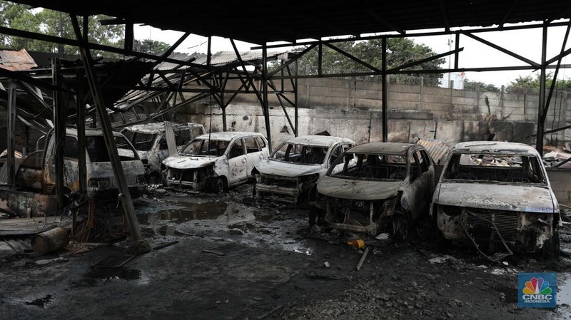 Warga melewati kendaraan yang hangus terbakar di lokasi terdampak kebakaran Depo Pertamina Plumpang di Kampung Tanah Merah Bawah, Koja, Jakarta Utara, Sabtu (4/3/2023). (CNBC Indonesia/Tri Susilo)