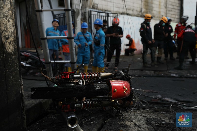 Warga melewati kendaraan yang hangus terbakar di lokasi terdampak kebakaran Depo Pertamina Plumpang di Kampung Tanah Merah Bawah, Koja, Jakarta Utara, Sabtu (4/3/2023). (CNBC Indonesia/Tri Susilo)