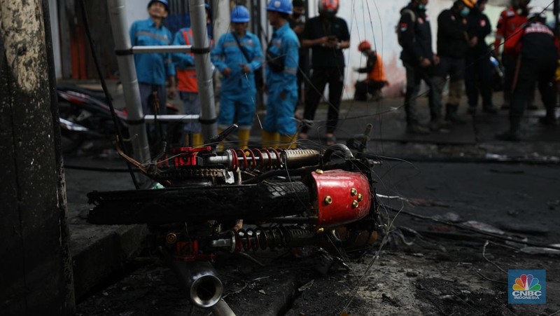 Warga melewati kendaraan yang hangus terbakar di lokasi terdampak kebakaran Depo Pertamina Plumpang di Kampung Tanah Merah Bawah, Koja, Jakarta Utara, Sabtu (4/3/2023). (CNBC Indonesia/Tri Susilo)