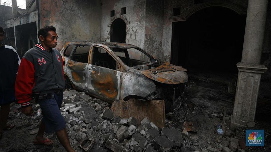Warga melewati kendaraan yang hangus terbakar di lokasi terdampak kebakaran Depo Pertamina Plumpang di Kampung Tanah Merah Bawah, Koja, Jakarta Utara, Sabtu (4/3/2023). (CNBC Indonesia/Tri Susilo)