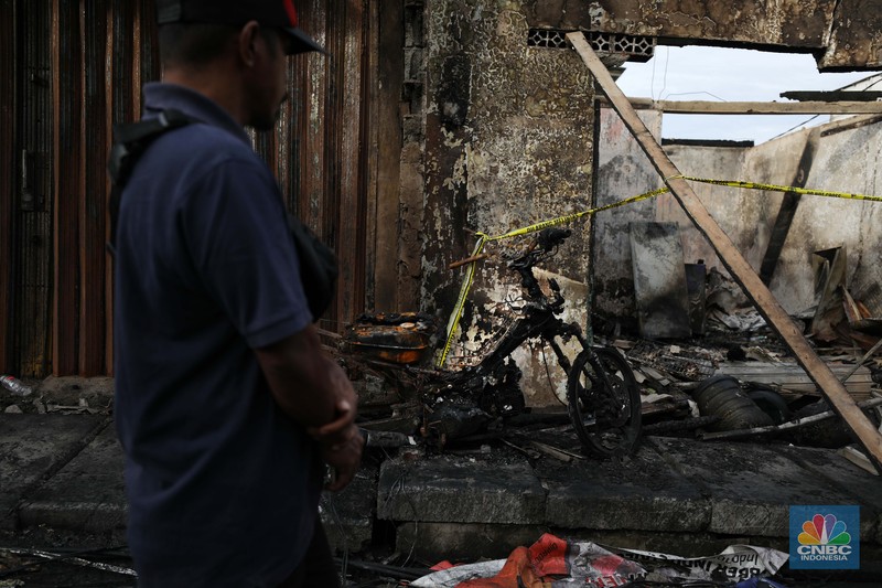 Warga melewati kendaraan yang hangus terbakar di lokasi terdampak kebakaran Depo Pertamina Plumpang di Kampung Tanah Merah Bawah, Koja, Jakarta Utara, Sabtu (4/3/2023). (CNBC Indonesia/Tri Susilo)