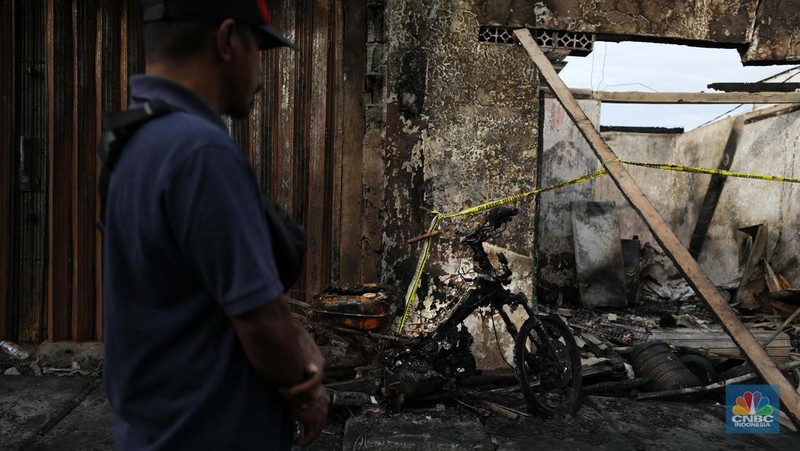 Warga melewati kendaraan yang hangus terbakar di lokasi terdampak kebakaran Depo Pertamina Plumpang di Kampung Tanah Merah Bawah, Koja, Jakarta Utara, Sabtu (4/3/2023). (CNBC Indonesia/Tri Susilo)