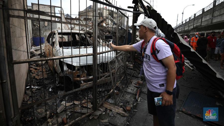 Warga melewati kendaraan yang hangus terbakar di lokasi terdampak kebakaran Depo Pertamina Plumpang di Kampung Tanah Merah Bawah, Koja, Jakarta Utara, Sabtu (4/3/2023). (CNBC Indonesia/Tri Susilo)