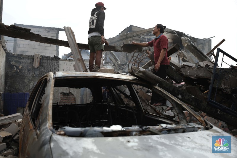 Warga melewati kendaraan yang hangus terbakar di lokasi terdampak kebakaran Depo Pertamina Plumpang di Kampung Tanah Merah Bawah, Koja, Jakarta Utara, Sabtu (4/3/2023). (CNBC Indonesia/Tri Susilo)