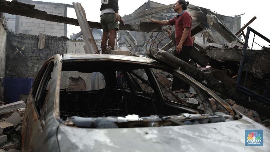 Warga melewati kendaraan yang hangus terbakar di lokasi terdampak kebakaran Depo Pertamina Plumpang di Kampung Tanah Merah Bawah, Koja, Jakarta Utara, Sabtu (4/3/2023). (CNBC Indonesia/Tri Susilo)