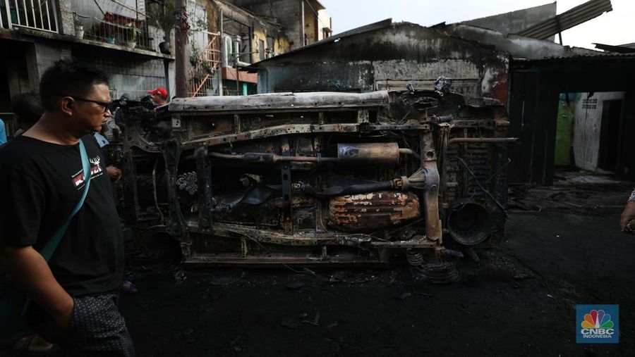 Warga melewati kendaraan yang hangus terbakar di lokasi terdampak kebakaran Depo Pertamina Plumpang di Kampung Tanah Merah Bawah, Koja, Jakarta Utara, Sabtu (4/3/2023). (CNBC Indonesia/Tri Susilo)