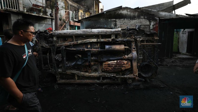 Warga melewati kendaraan yang hangus terbakar di lokasi terdampak kebakaran Depo Pertamina Plumpang di Kampung Tanah Merah Bawah, Koja, Jakarta Utara, Sabtu (4/3/2023). (CNBC Indonesia/Tri Susilo)