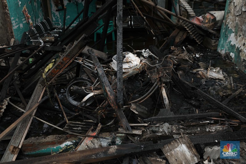 Warga melewati kendaraan yang hangus terbakar di lokasi terdampak kebakaran Depo Pertamina Plumpang di Kampung Tanah Merah Bawah, Koja, Jakarta Utara, Sabtu (4/3/2023). (CNBC Indonesia/Tri Susilo)