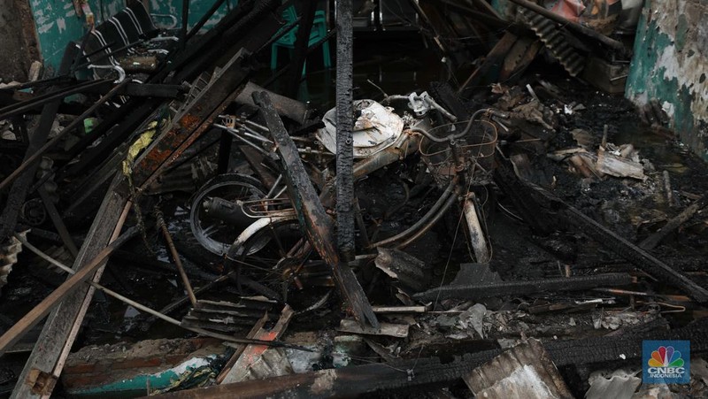 Warga melewati kendaraan yang hangus terbakar di lokasi terdampak kebakaran Depo Pertamina Plumpang di Kampung Tanah Merah Bawah, Koja, Jakarta Utara, Sabtu (4/3/2023). (CNBC Indonesia/Tri Susilo)