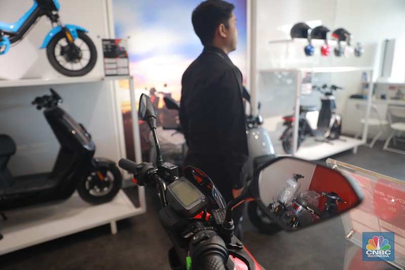 Salah satu pegawai mekanik motor listrik melihat motor listrik di salah satu showroom di kawasan Arteri, Senin (11/10/2022). (CNBC Indonesia/ Muhammad Sabki)