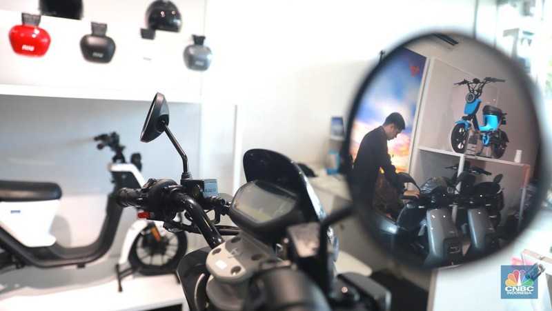 Salah satu pegawai mekanik motor listrik melihat motor listrik di salah satu showroom di kawasan Arteri, Senin (11/10/2022). (CNBC Indonesia/ Muhammad Sabki)