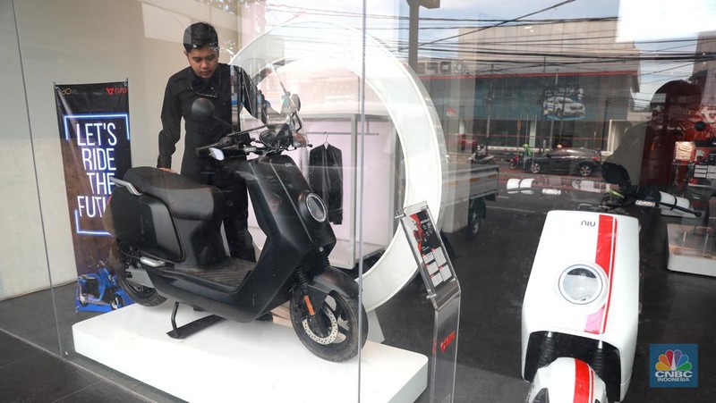 Salah satu pegawai mekanik motor listrik melihat motor listrik di salah satu showroom di kawasan Arteri, Senin (11/10/2022). (CNBC Indonesia/ Muhammad Sabki)