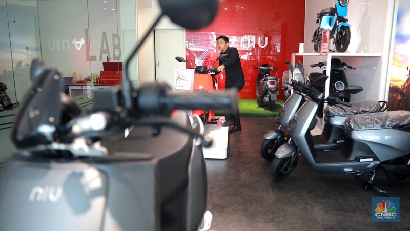 Salah satu pegawai mekanik motor listrik melihat motor listrik di salah satu showroom di kawasan Arteri, Senin (11/10/2022). (CNBC Indonesia/ Muhammad Sabki)