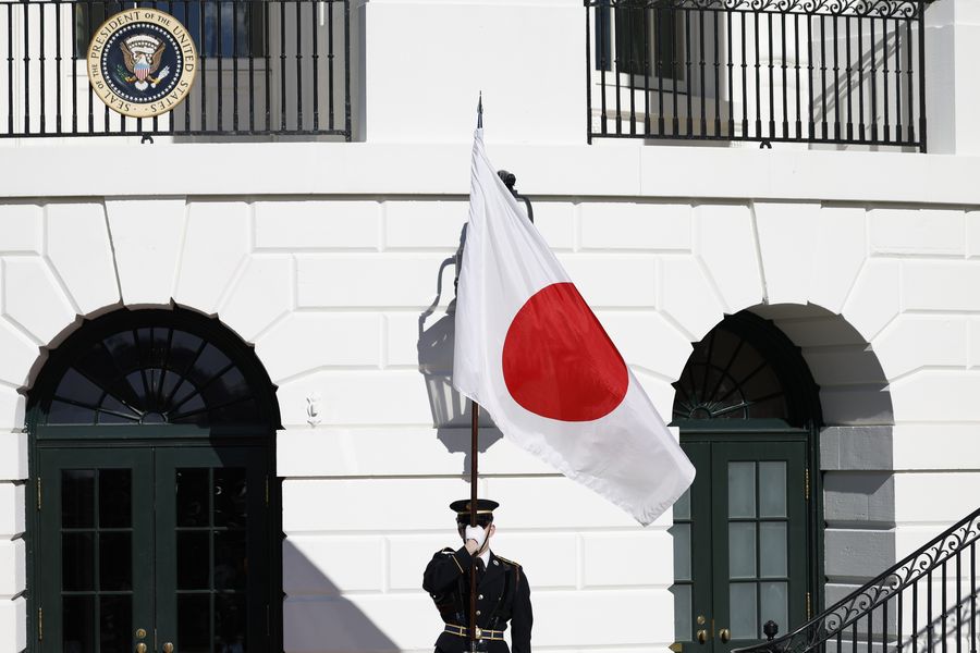 Seorang anggota pasukan kehormatan memegang bendera nasional Jepang. (Bloomberg via Getty Images)