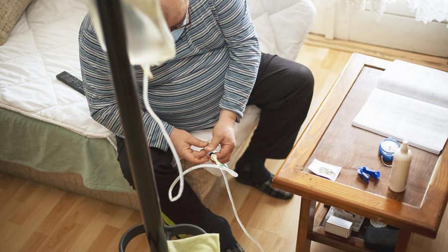 Senior man connecting peritoneal dialysis with catheter at home