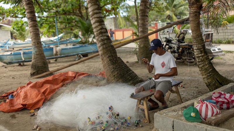 Relawan menggunakan alat pelindung diri (APD) sedang membersihkan tumpahan minyak dari kapal tanker bahan bakar MT Princess Empress yang tenggelam, di pantai Pola, di provinsi Oriental Mindoro, Filipina, (7/3/2023). (REUTERS/ELOISA LOPEZ)