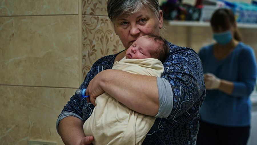 Seorang staf perawat memeluk bayi yang sedang tidur di kamar bayi darurat di bawah tanah di pinggiran Kyiv, Ukraina, Minggu, 20 Maret 2022. Lebih dari selusin bayi pengganti kelahiran Ukraina bersama dengan staf perawat pusat ibu pengganti tinggal di bawah tanah di tempat penampungan setelah Pengeboman Rusia mendarat hampir 200 meter dari pembibitan mereka di atas tanah awal Maret. Perang Rusia-Ukraina mempersulit evakuasi bayi-bayi ini. (MARCUS YAM / LOS ANGELES TIMES)