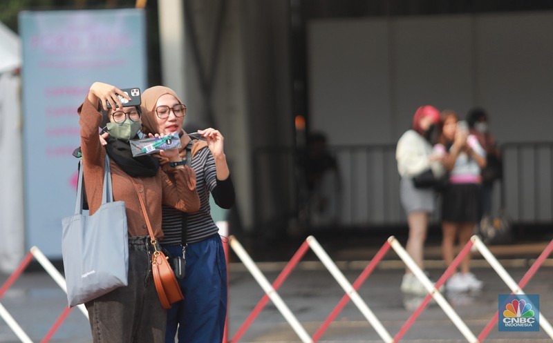 Pengunjung berfoto di depan banner penukaran tiket Blackpink, di Senayan, Jakarta, Jumat, 10/3. Seperti diketahui konser BLACKPINK akan digelar besok selama dua hari di Stadion Utama Gelora Bung Karno, yakni pada 11 dan 12 Maret 2023 mendatang. (CNBC Indonesia/ Muhammad Sabki)