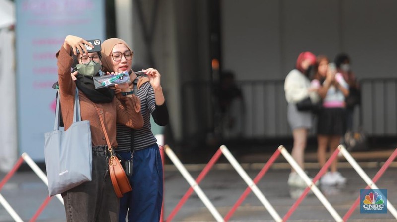 Pengunjung berfoto di depan banner penukaran tiket Blackpink, di Senayan, Jakarta, Jumat, 10/3. Seperti diketahui konser BLACKPINK akan digelar besok selama dua hari di Stadion Utama Gelora Bung Karno, yakni pada 11 dan 12 Maret 2023 mendatang. (CNBC Indonesia/ Muhammad Sabki)