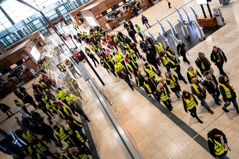 Petugas keamanan yang mogok berkumpul di luar aula Terminal 1 di Bandara Berlin Brandenburg pada 13 Maret 2023 di Schoenefeld, Jerman. Personil keamanan di bandara Berlin, Bremen, Hamburg dan Hanover hari ini mogok untuk menuntut upah yang lebih tinggi. Pekerja sektor publik dari berbagai profesi melakukan pemogokan di seluruh Jerman minggu ini dalam upaya Ver.di, serikat pekerja yang mewakili mereka, untuk menekan pemberi kerja dalam negosiasi upah yang sedang berlangsung. (Sean Gallup/Getty Images)