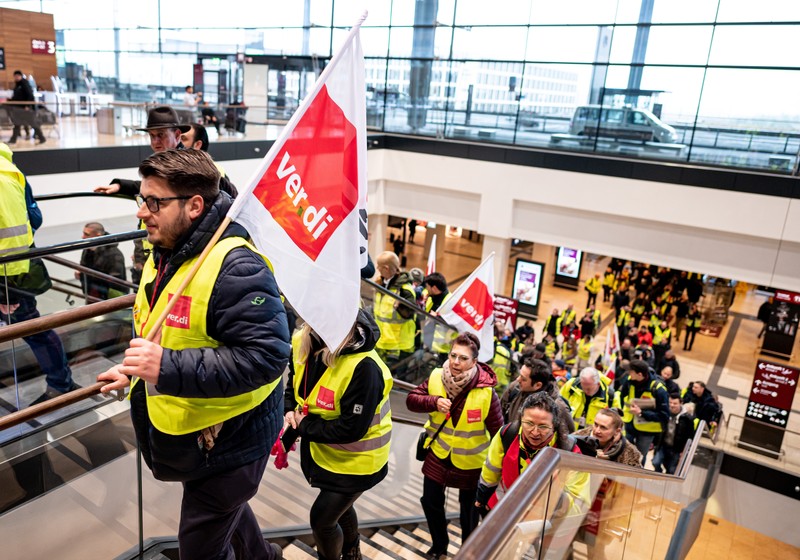 Petugas keamanan yang mogok berkumpul di luar aula Terminal 1 di Bandara Berlin Brandenburg pada 13 Maret 2023 di Schoenefeld, Jerman. Personil keamanan di bandara Berlin, Bremen, Hamburg dan Hanover hari ini mogok untuk menuntut upah yang lebih tinggi. Pekerja sektor publik dari berbagai profesi melakukan pemogokan di seluruh Jerman minggu ini dalam upaya Ver.di, serikat pekerja yang mewakili mereka, untuk menekan pemberi kerja dalam negosiasi upah yang sedang berlangsung. (Sean Gallup/Getty Images)
