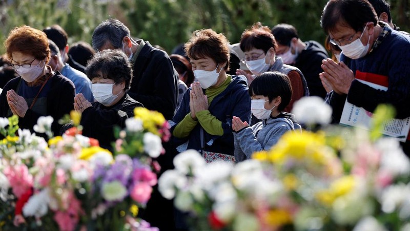 Orang-orang berkumpul di Natori, Prefektur Miyagi, Jepang untuk mengenang para korban pada peringatan 12 tahun gempa bumi, tsunami, dan bencana nuklir 2011. (JIJI PRESS/AFP via Getty Images/STR)