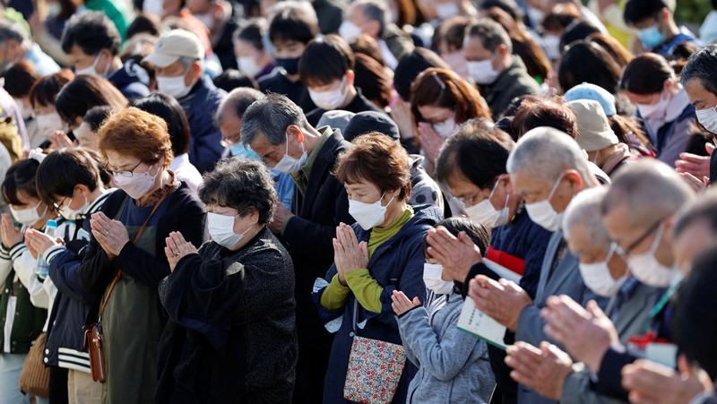 Orang-orang berkumpul di Natori, Prefektur Miyagi, Jepang untuk mengenang para korban pada peringatan 12 tahun gempa bumi, tsunami, dan bencana nuklir 2011. (JIJI PRESS/AFP via Getty Images/STR)