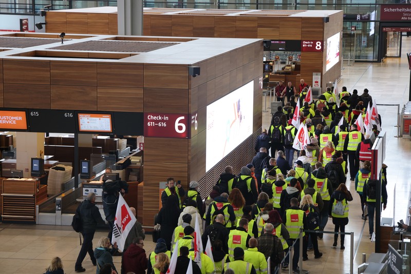 Petugas keamanan yang mogok berkumpul di luar aula Terminal 1 di Bandara Berlin Brandenburg pada 13 Maret 2023 di Schoenefeld, Jerman. Personil keamanan di bandara Berlin, Bremen, Hamburg dan Hanover hari ini mogok untuk menuntut upah yang lebih tinggi. Pekerja sektor publik dari berbagai profesi melakukan pemogokan di seluruh Jerman minggu ini dalam upaya Ver.di, serikat pekerja yang mewakili mereka, untuk menekan pemberi kerja dalam negosiasi upah yang sedang berlangsung. (Sean Gallup/Getty Images)