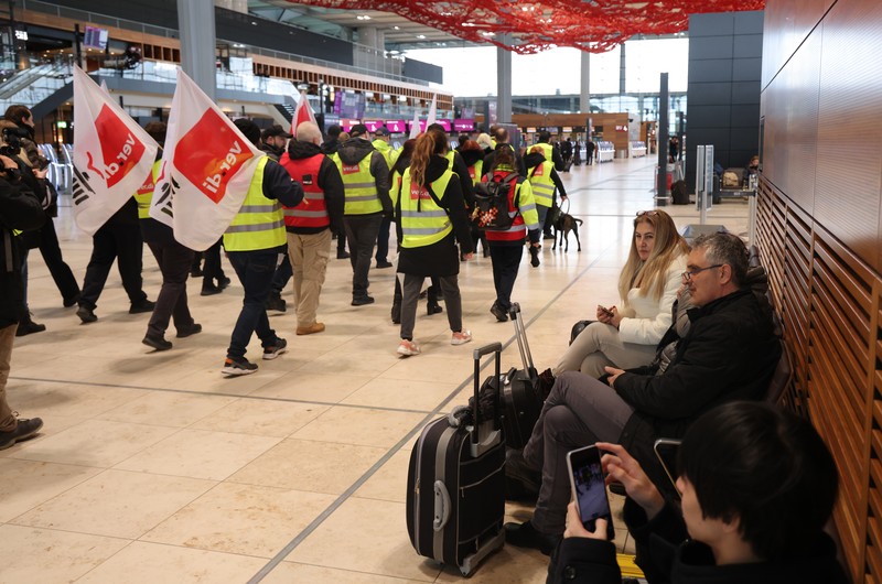 Petugas keamanan yang mogok berkumpul di luar aula Terminal 1 di Bandara Berlin Brandenburg pada 13 Maret 2023 di Schoenefeld, Jerman. Petugas keamanan yang mogok berkumpul di luar aula Terminal 1 di Bandara Berlin Brandenburg pada 13 Maret 2023 di Schoenefeld, Jerman. Personil keamanan di bandara Berlin, Bremen, Hamburg dan Hanover hari ini mogok untuk menuntut upah yang lebih tinggi. Pekerja sektor publik dari berbagai profesi melakukan pemogokan di seluruh Jerman minggu ini dalam upaya Ver.di, serikat pekerja yang mewakili mereka, untuk menekan pemberi kerja dalam negosiasi upah yang sedang berlangsung. (Sean Gallup/Getty Images)