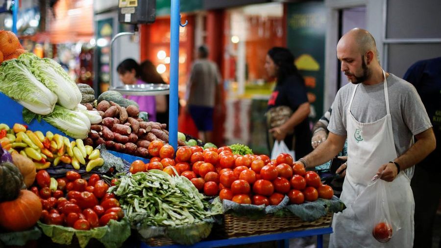 A vegetable seller grabs tomatoes at a greengrocery store in a local market, as Argentina's annual inflation rate tore past 100% in February, the country's statistics agency said on Tuesday, the first time it has hit triple figures since a period of hyperinflation in 1991, over three decades ago, in Buenos Aires, Argentina March 14, 2023. REUTERS/Agustin Marcarian