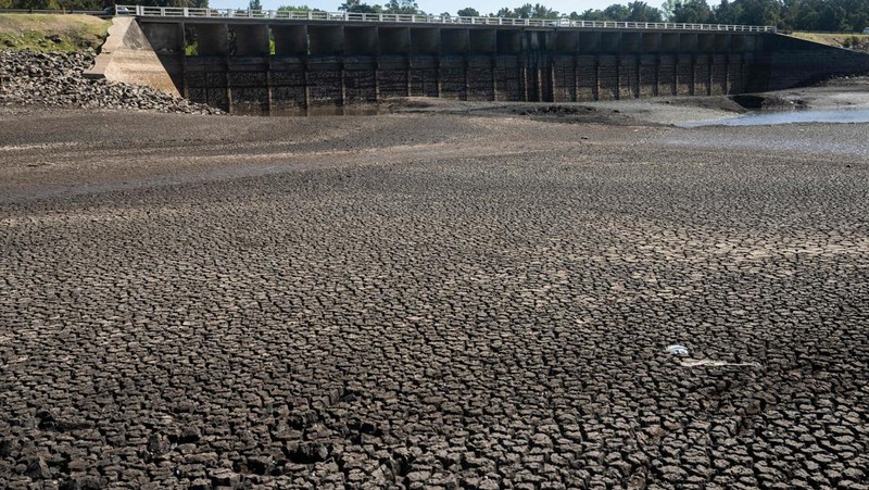Seorang pria memotret waduk Canelon Grande yang kering di utara Canelones, Uruguay selatan, pada 14 Maret 2023, saat negara itu mengalami kekeringan parah. - Tujuan utama waduk adalah untuk memasok air minum ke wilayah Metropolitan Montevideo, selain itu juga digunakan dalam sistem irigasi di daerah tersebut. (PABLO PORCIUNCULA/AFP via Getty Images)
