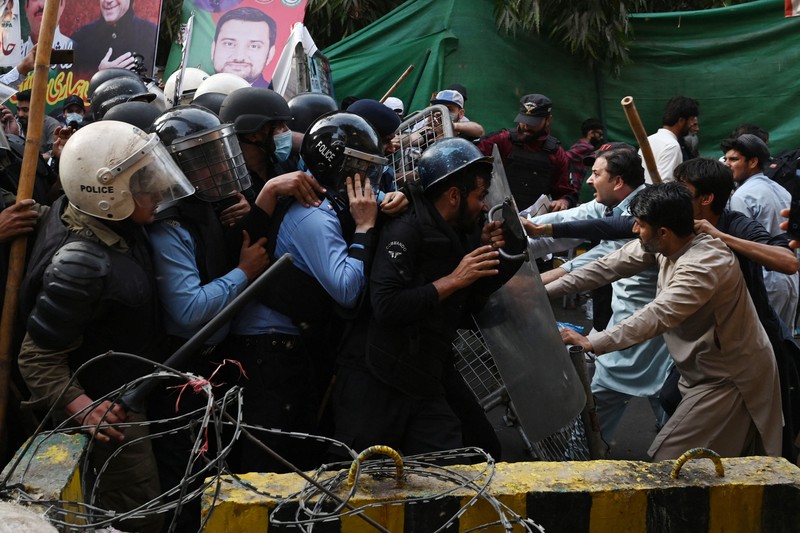 Polisi anti huru hara mencoba memukul mundur pendukung mantan perdana menteri Imran Khan yang berkumpul di luar rumah Khan untuk mencegah petugas menangkapnya, di Lahore, Pakistan pada 14 Maret 2023. Polisi anti huru hara mencoba memukul mundur pendukung mantan perdana menteri Imran Khan yang berkumpul di luar rumah Khan untuk mencegah petugas menangkapnya, di Lahore, Pakistan pada 14 Maret 2023. Para pengunjuk rasa bentrok dengan polisi. Polisi, yang mengenakan pakaian anti huru hara dan memegang perisai, menggunakan meriam air untuk menghalau para aktivis pelempar batu dari partai Pakistan Tehreek-e-Insaf (PTI) Khan, yang telah menguasai pintu masuk utama ke kediaman pemimpin partai mereka. Beberapa pekerja PTI, menurut sumber kepolisian, ditahan. (Rana Irfan Ali/Anadolu Agency via Getty Images)