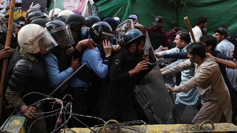 Polisi anti huru hara mencoba memukul mundur pendukung mantan perdana menteri Imran Khan yang berkumpul di luar rumah Khan untuk mencegah petugas menangkapnya, di Lahore, Pakistan pada 14 Maret 2023. Para pengunjuk rasa bentrok dengan polisi. Polisi, yang mengenakan pakaian anti huru hara dan memegang perisai, menggunakan meriam air untuk menghalau para aktivis pelempar batu dari partai Pakistan Tehreek-e-Insaf (PTI) Khan, yang telah menguasai pintu masuk utama ke kediaman pemimpin partai mereka. Beberapa pekerja PTI, menurut sumber kepolisian, ditahan. (Rana Irfan Ali/Anadolu Agency via Getty Images)